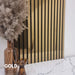 Decorative wall with gold and black slat wall panel, vase with dried plants on marble surface.