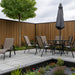 Garden setting with patio furniture, table, chairs, and umbrella against a oak slat clad fence.