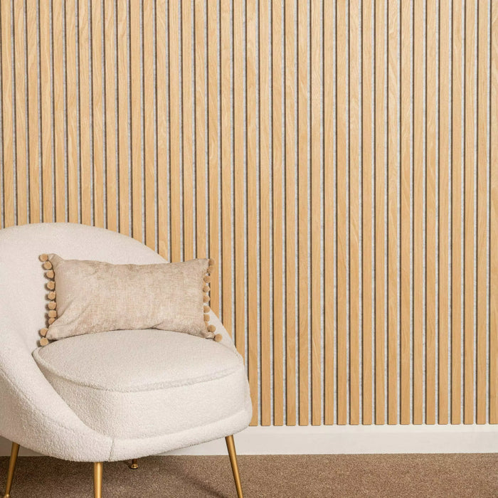 Beige chair with a decorative pillow against a oak on a light grey wall.