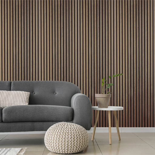 Modern living room with a gray sofa, white pouf, and small table against a walnut wooden panel wall.