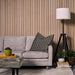 Living room with a gray sofa, patterned pillow, and oak slat wall panels