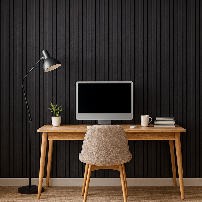 Modern home office with wooden desk, chair, computer monitor, lamp, and decor against a black acoustic panelled wall.
